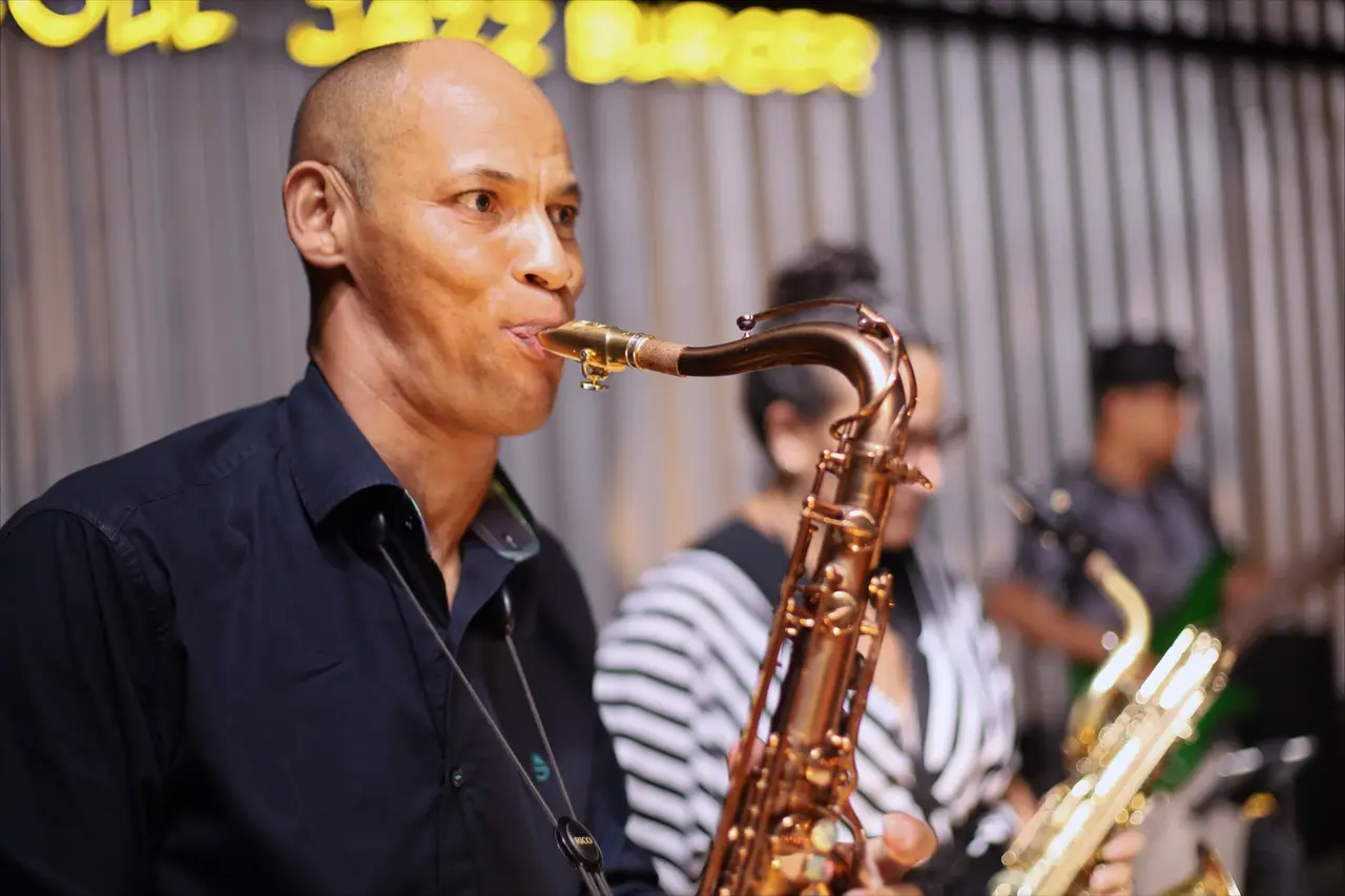 Saxofonista tocando na Santa Tereza, com a banda atrás